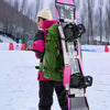 A snowboarder carrying a snowboard equipped with XCMAN 360 Seco bindings in a snowy mountain resort setting
